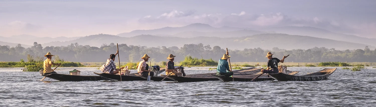 Row of five fishermen in boats with distant mountains on Inle Lake in Myanmar